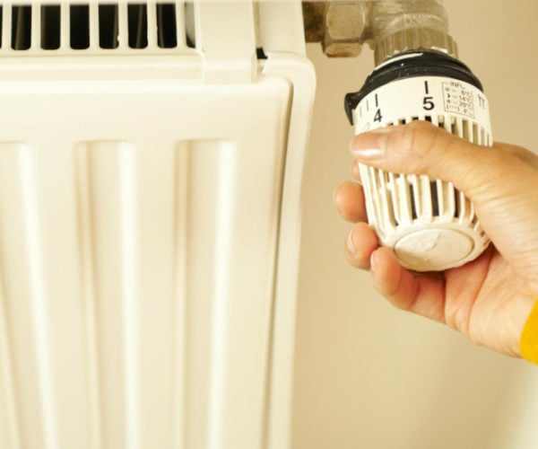 Hand turning a thermostatic valve on a radiator
