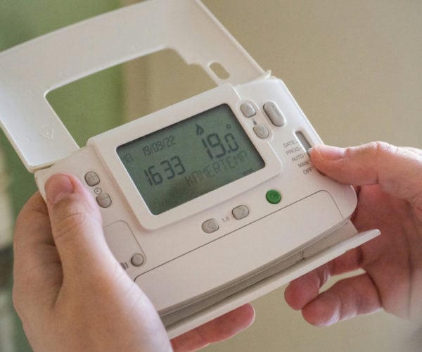 Hands adjusting a digital thermostat