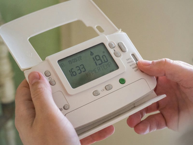 Hands adjusting a digital thermostat