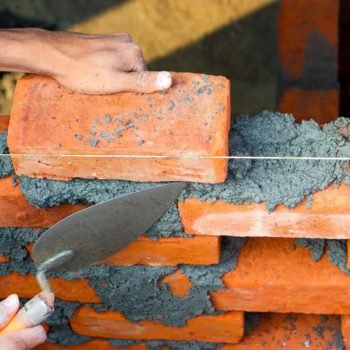 Man building a brick wall using a trowel and mortar