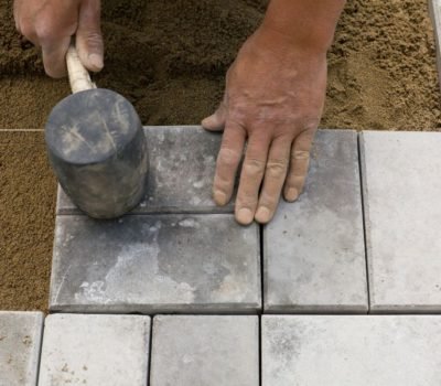 Worker holding rubber mallet placing blocks on sand