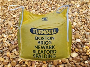 Pea Gravel background with yellow Turnbull branded bulk bag in foreground