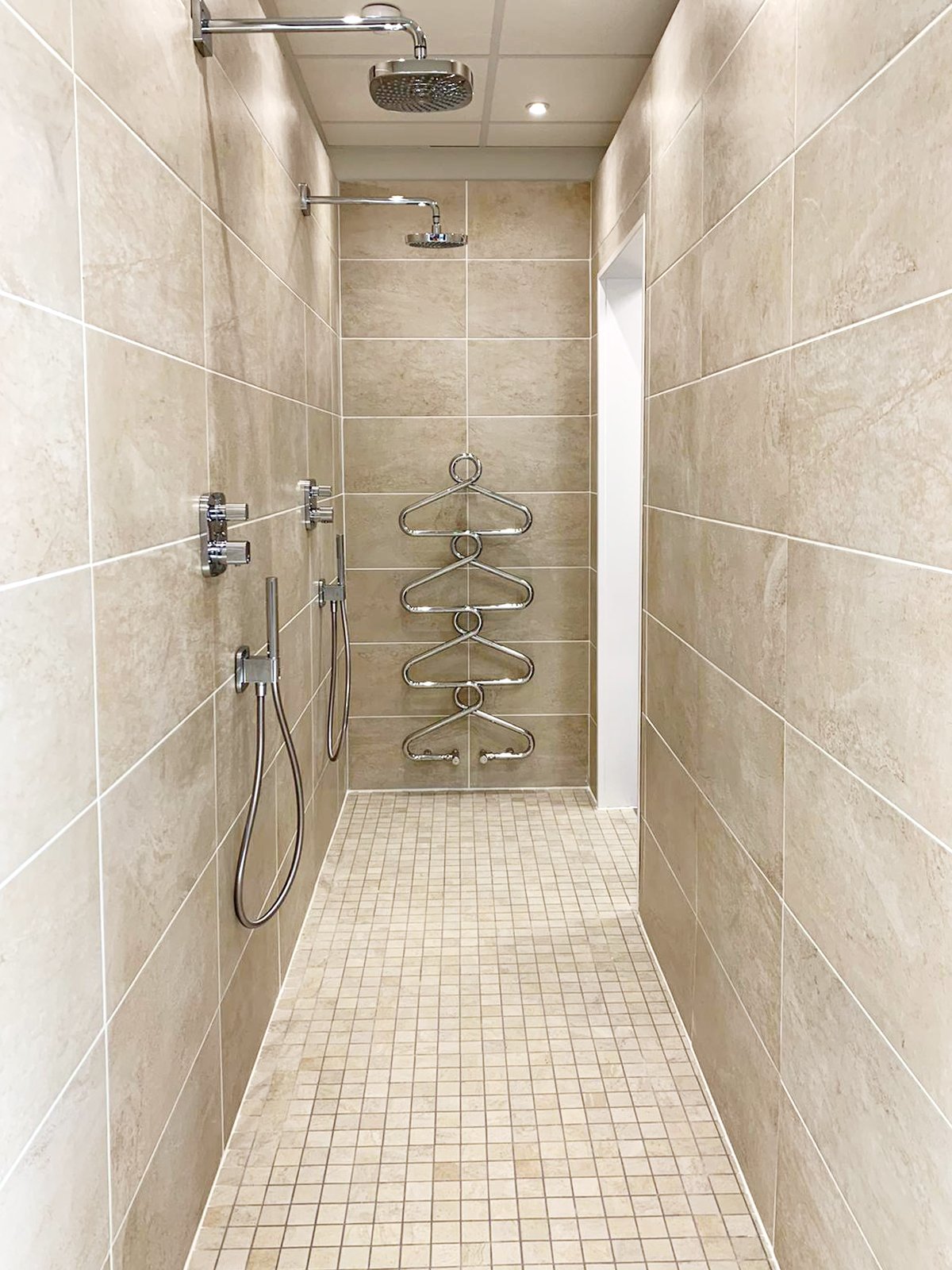 Walk-in twin shower heads in enclosed wet room area of a modern bathroom