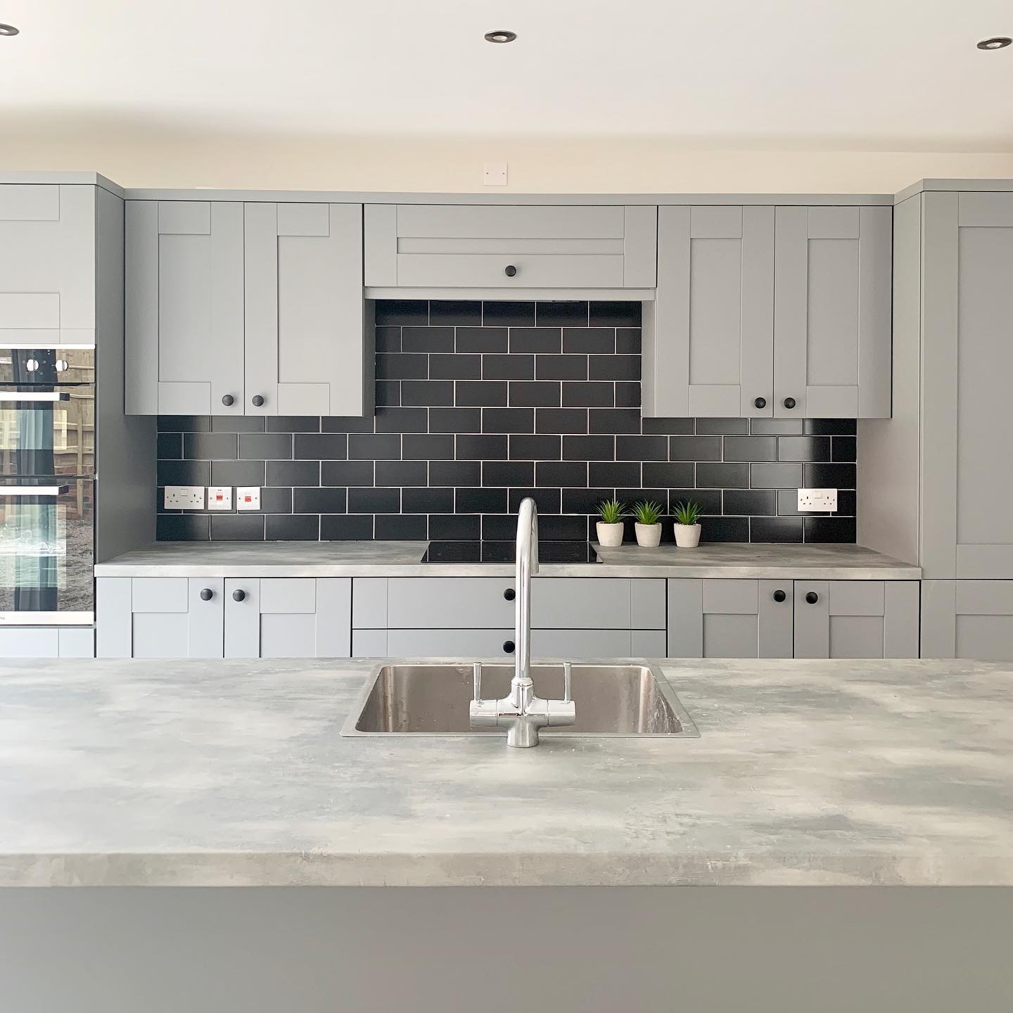 Charworth Homes - grey kitchen with statement tiles in black
